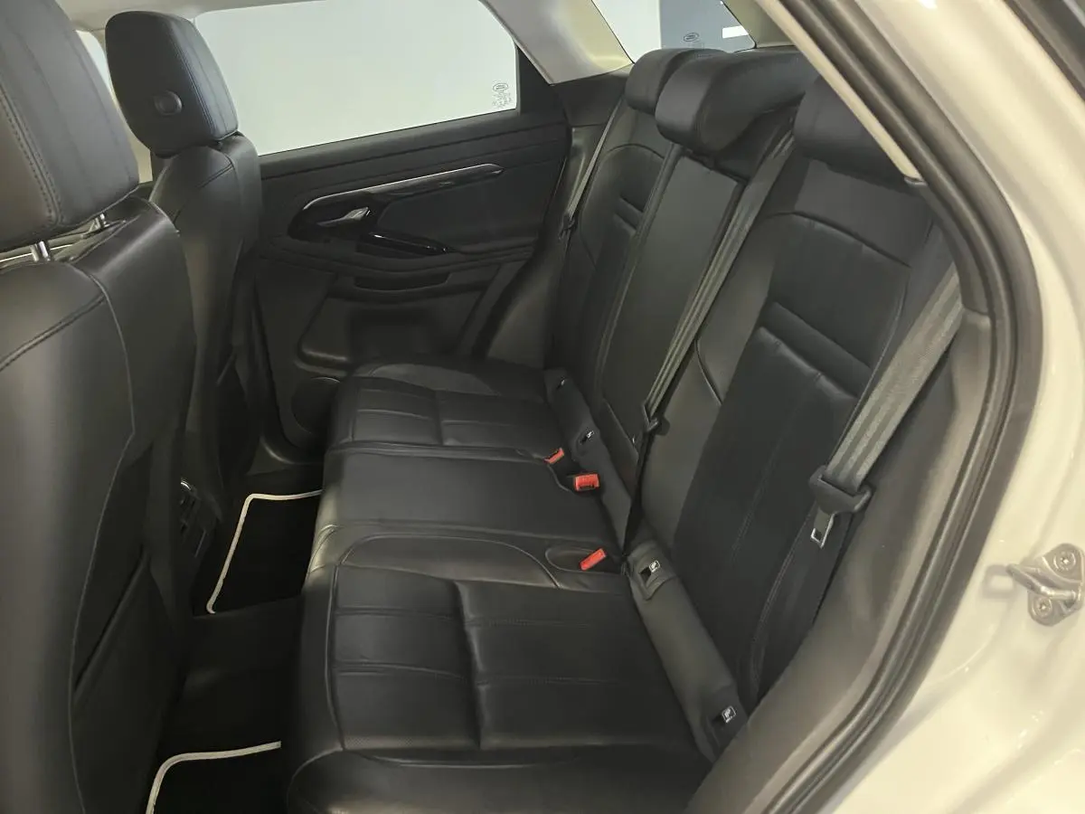 Vue intérieure côté droit des sièges arrière en cuir noir du Range Rover Evoque blanc 2020, avec ceintures et appuie-têtes visibles.