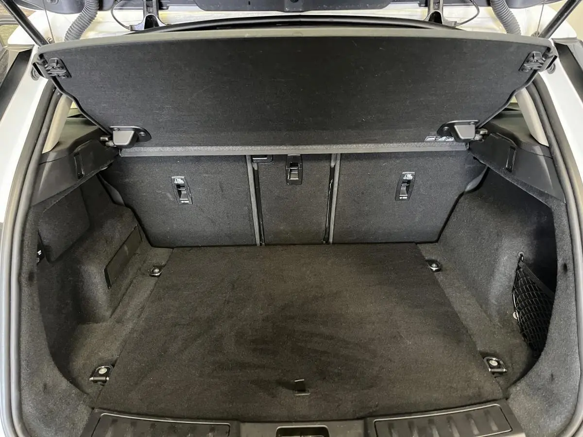 Coffre ouvert vu de l'arrière d'un Range Rover Evoque blanc, montrant l'espace de chargement et la tablette cache-bagages.