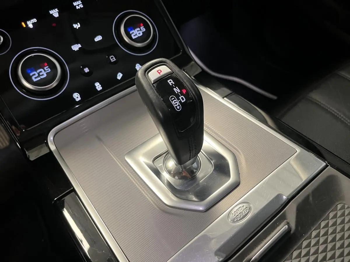 Le levier de vitesses automatique noir et argenté du Range Rover Evoque 2020 vu de près avec commandes de climatisation en arrière-plan.