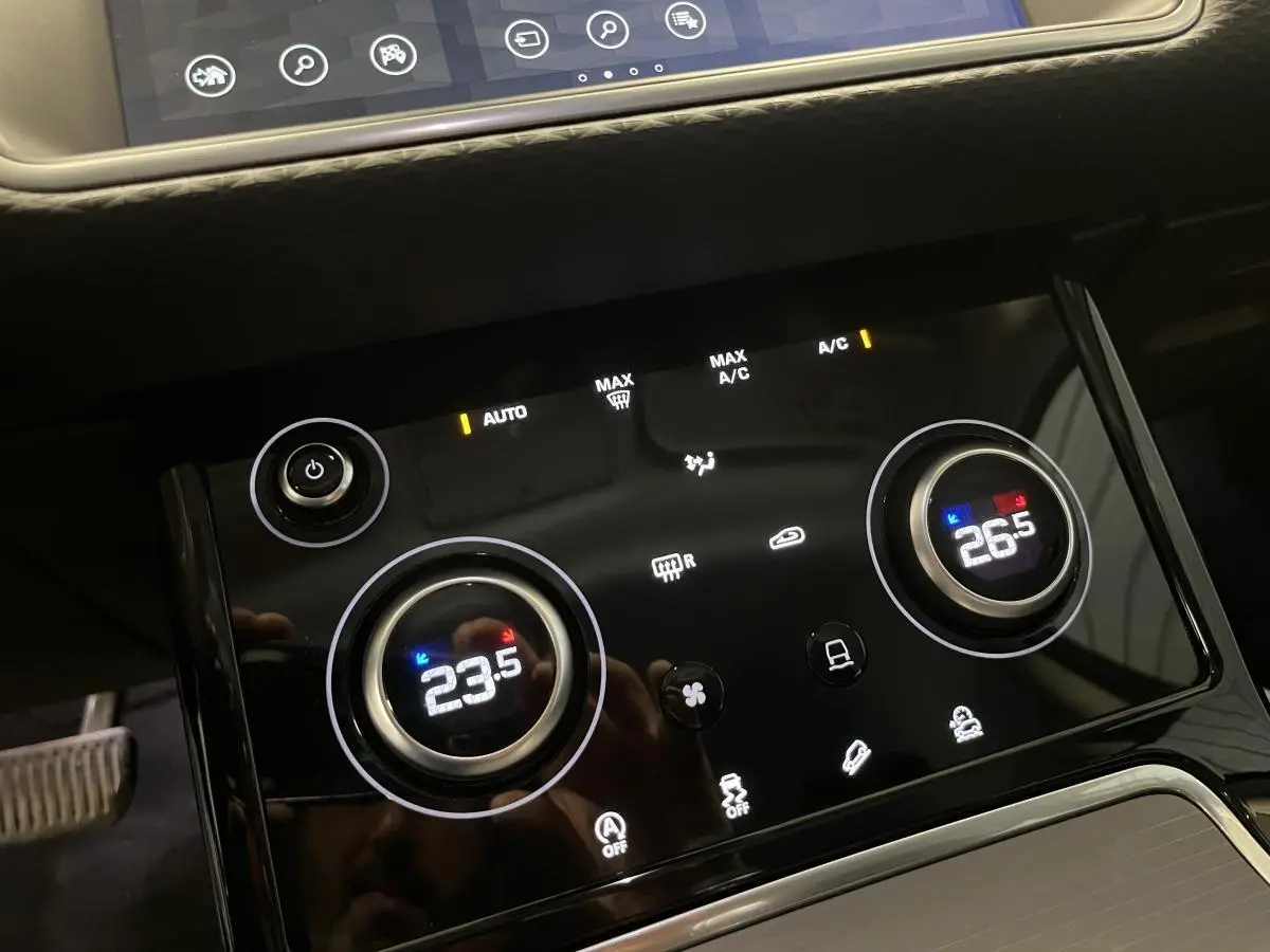 Gros plan sur la console centrale tactile du Range Rover Evoque 2020, affichant la climatisation bi-zone à 23,5°C et 26,5°C.