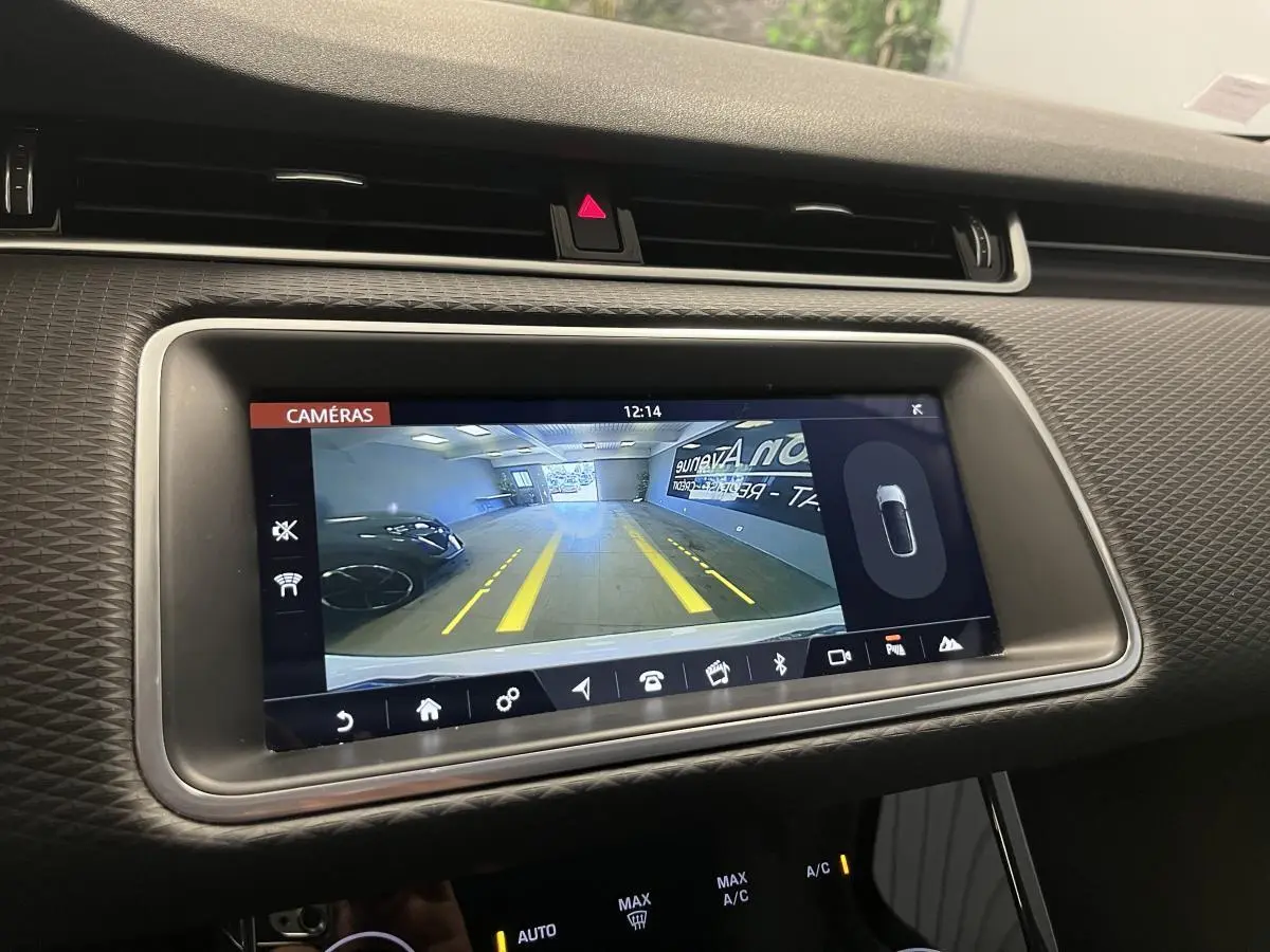 Écran tactile central montrant la caméra de recul du Range Rover Evoque blanc, avec lignes de guidage jaunes visibles.