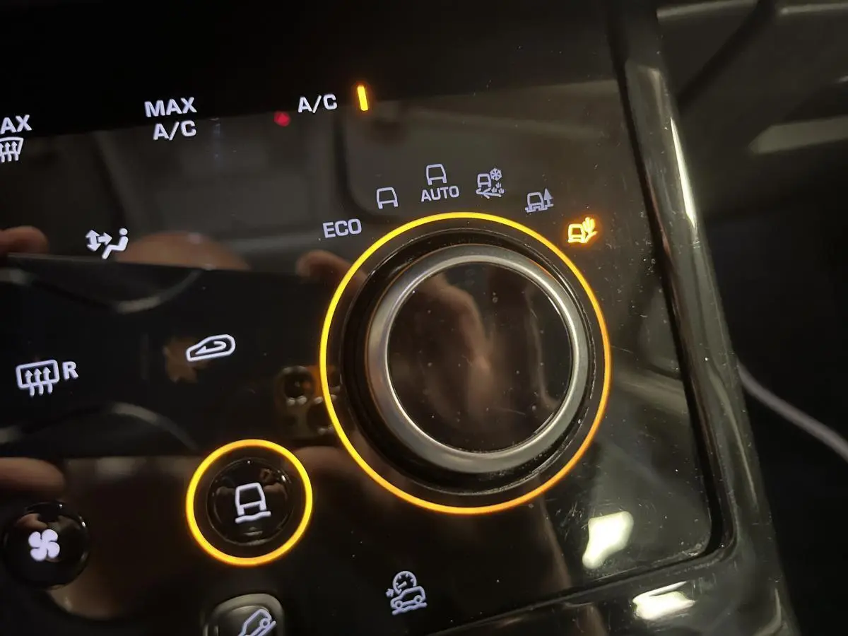 Gros plan sur la molette de sélection des modes de conduite du Range Rover Evoque blanc, éclairage orange autour.