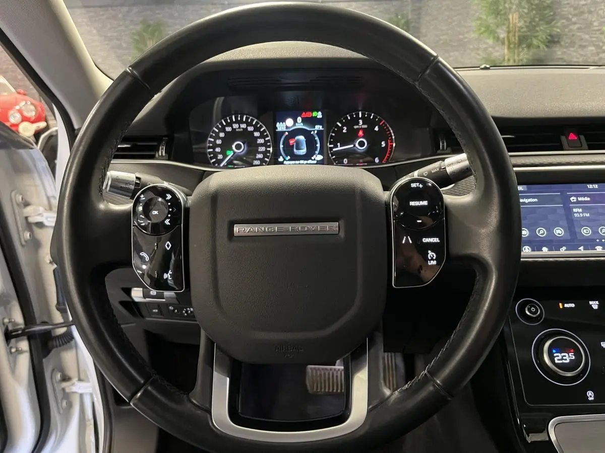 Vue rapprochée du volant noir de la Range Rover Evoque 2020 avec commandes intégrées et tableau de bord numérique.