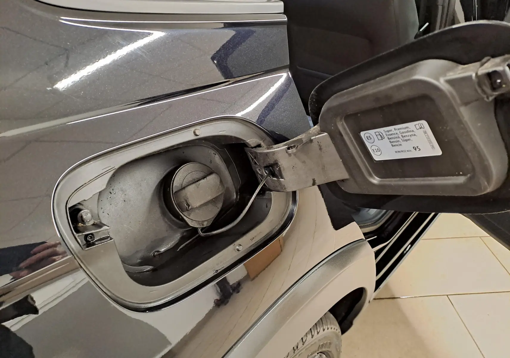 Gros plan sur la trappe à carburant ouverte côté gauche du Volkswagen Taigo noir intense nacré, avec bouchon essence visible.