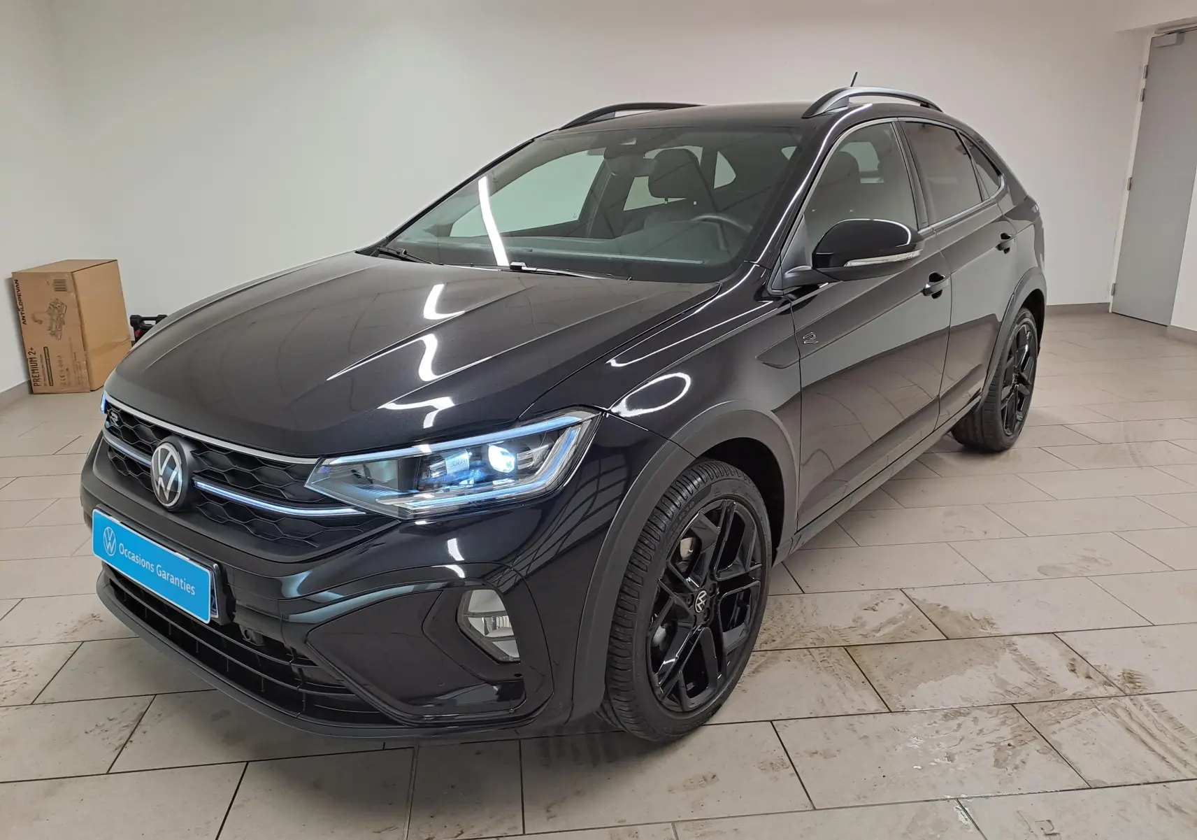 Volkswagen Taigo 1.5 TSI R-Line noir intense nacré, vue 3/4 avant avec jantes noires 18 pouces et feux LED allumés.