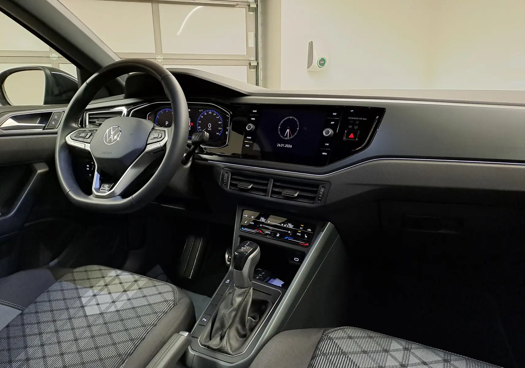 Vue intérieure avant gauche du Volkswagen Taigo 1.5 TSI R-Line 2025, avec volant cuir multifonctions et tableau de bord digital.