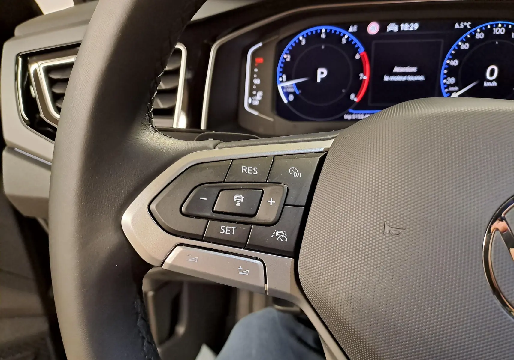 Gros plan sur la partie gauche du volant cuir du Volkswagen Taigo 2025 avec commandes de régulateur de vitesse et tableau de bord digital.