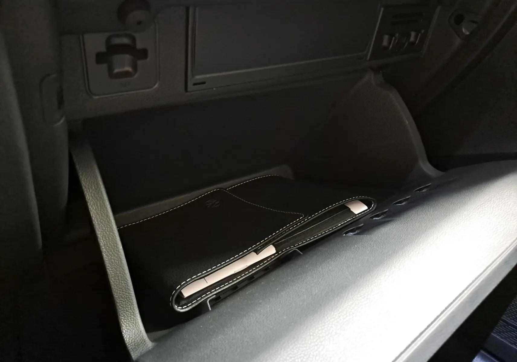 Gros plan sur la boîte à gants ouverte du Volkswagen Taigo 1.5 TSI 150 DSG7 R-Line Edition avec pochette noire à l'intérieur.