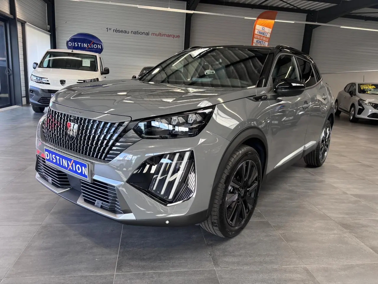 Peugeot 2008 gris selenium en 3/4 avant droit, avec jantes alliage noires et calandre noire distinctive.