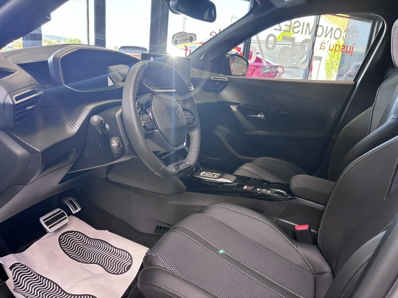 Intérieur de la Peugeot 2008 1.2i Hybrid GT 2026 vu côté conducteur, avec sellerie noire et volant compact cuir.