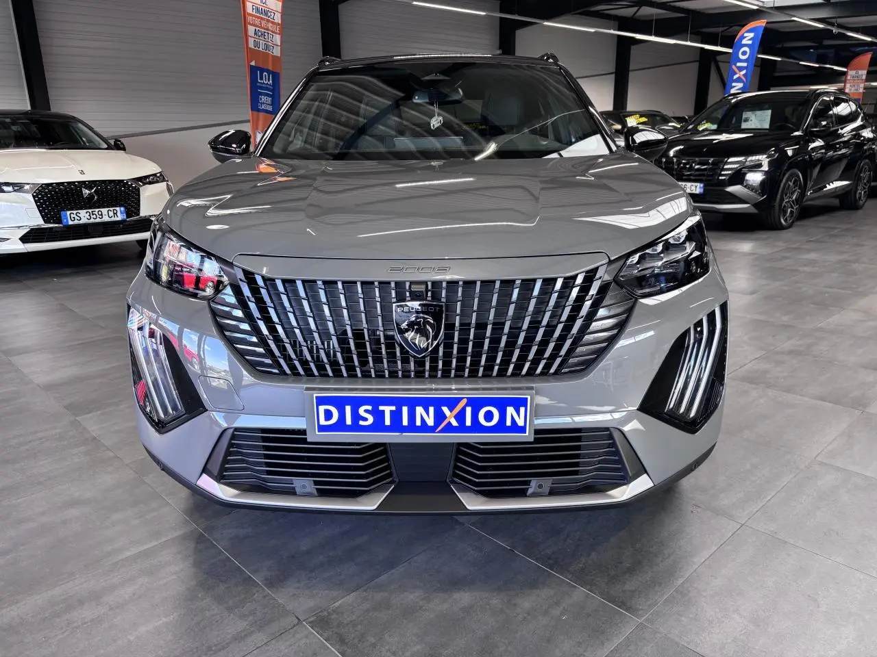 Vue avant d'un Peugeot 2008 gris selenium avec calandre noire verticale et feux LED distinctifs en forme de griffes.