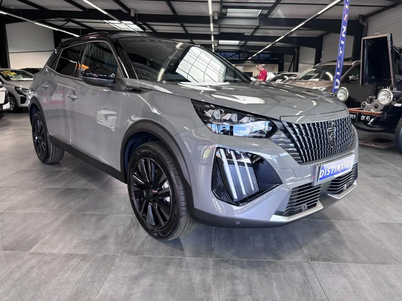 Peugeot 2008 gris selenium en 3/4 avant droit avec jantes noires bi-tons et calandre noire distinctive.