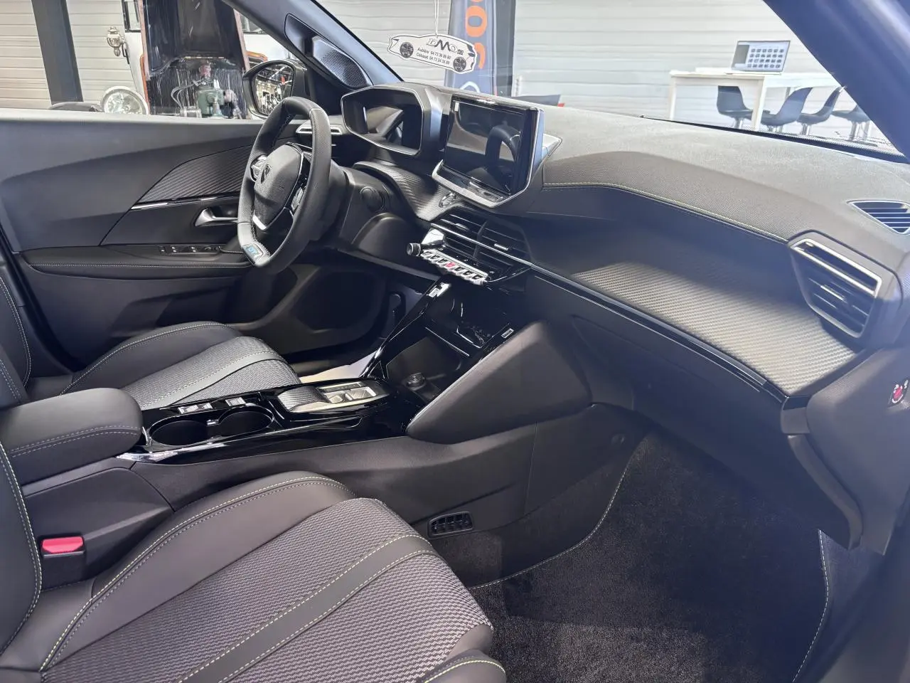 Vue intérieure côté conducteur du Peugeot 2008 1.2i Hybrid 145 GT, avec sellerie tissu et console centrale noire brillante.