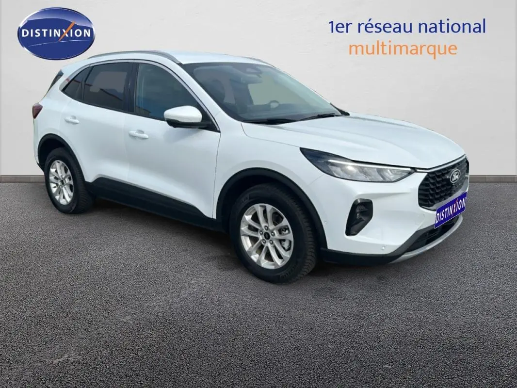 Ford Kuga blanc en 3/4 avant droit, avec barres de toit et jantes alliage 17 pouces visibles.