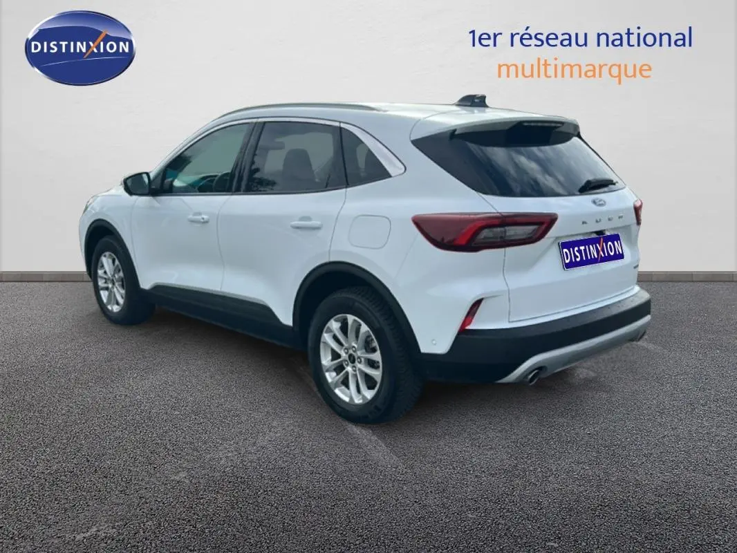 Vue 3/4 arrière droite d'un Ford Kuga blanc 2025 avec jantes alliage et barres de toit visibles.