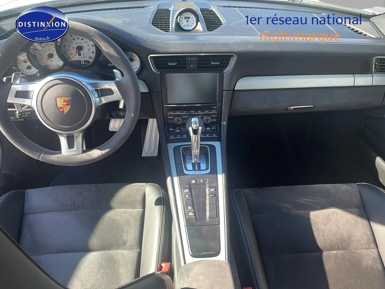 Vue intérieure de face du tableau de bord et console centrale d'une Porsche 911 GT3 991 avec volant cuir et sièges sport noirs.