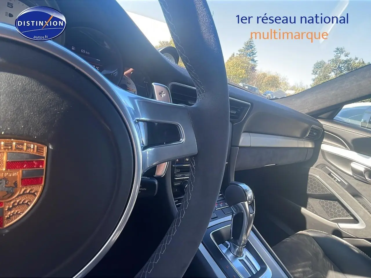 Intérieur de Porsche 911 GT3 blanc, vue côté conducteur sur volant sport, tableau de bord et levier de vitesse automatique.