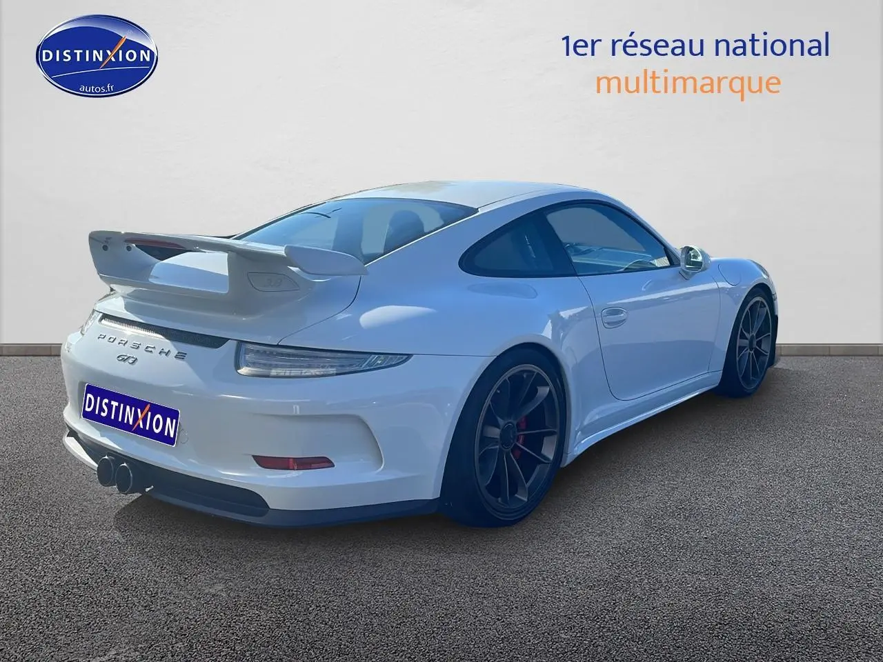 Vue 3/4 arrière droite d'une Porsche 911 (991) GT3 blanche avec becquet arrière et jantes noires.