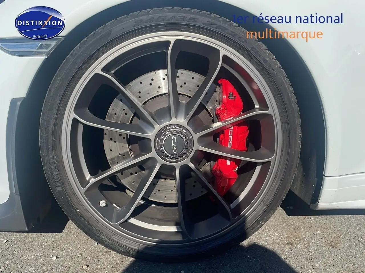 Gros plan sur la roue avant droite blanche d'une Porsche 911 (991) GT3 avec étrier de frein rouge et jante alu noire.