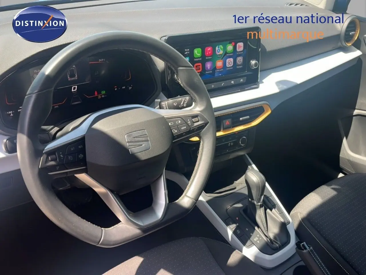 Vue intérieure centrée sur le volant et la console centrale du SEAT Arona 2025, avec écran tactile et détails noirs et blancs.