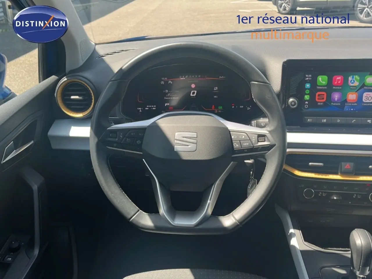 Vue intérieure centrée sur le volant noir du SEAT Arona 2025, avec tableau de bord digital et écran tactile coloré.