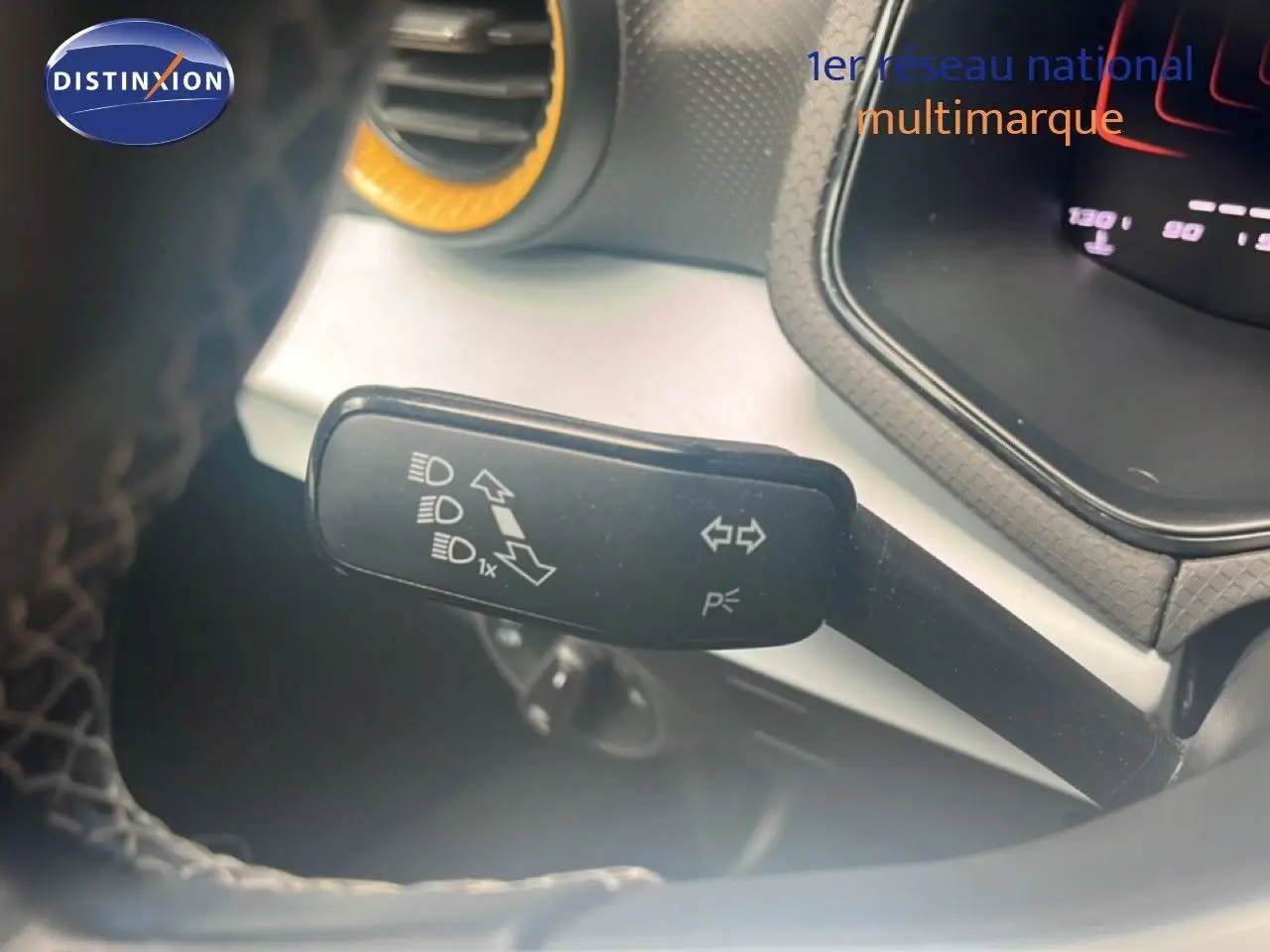 Gros plan sur la manette de clignotant et feux du tableau de bord d’un SEAT Arona 2025 bleu saphir métal.