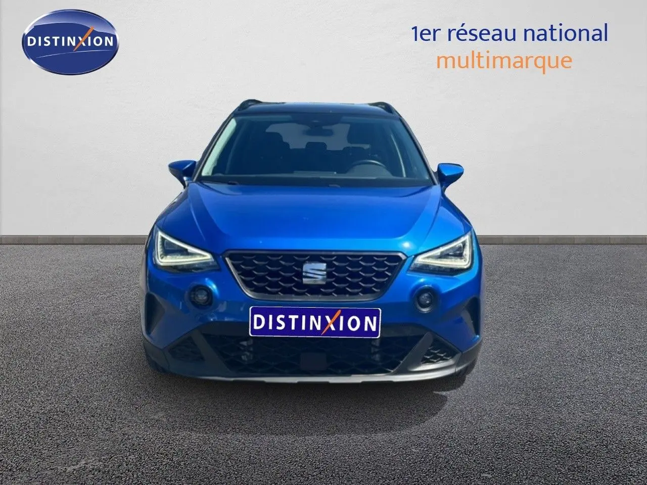 Vue avant d'un SEAT Arona bleu saphir métal avec toit noir, mettant en valeur sa calandre et ses phares LED distinctifs.