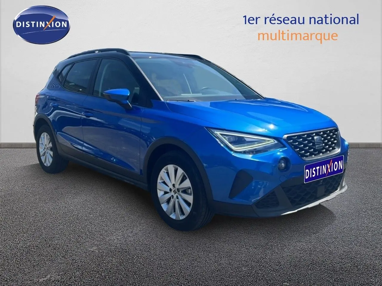SEAT Arona bleu saphir métal avec toit noir, vue 3/4 avant droit, calandre et optiques LED visibles.