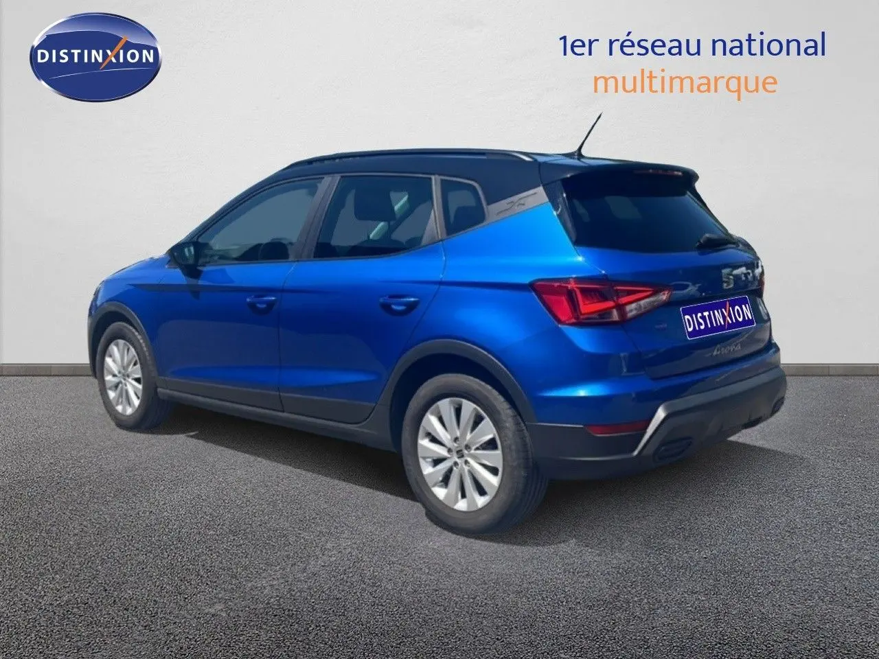 Vue 3/4 arrière droite d'un SEAT Arona bleu saphir métal avec toit noir, stationné sur sol gris.
