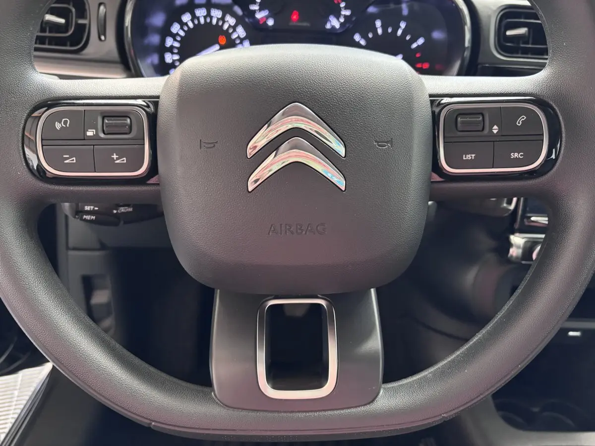 Gros plan sur le volant multifonctions noir de la Citroën C3 PureTech 110 BVM6 PLUS avec logo chromé central.