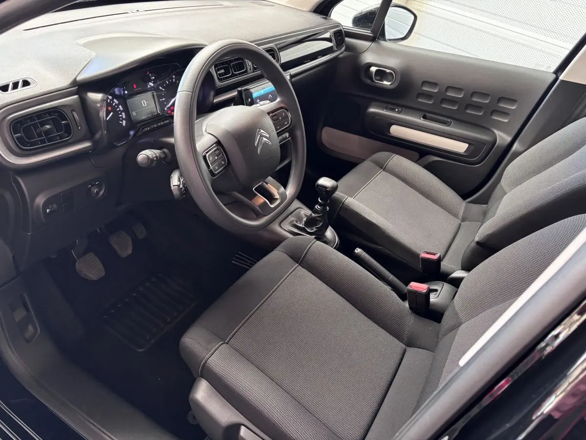 Intérieur avant de la Citroën C3 PureTech 110 noir, vue côté conducteur montrant volant multifonctions et sièges tissu gris.