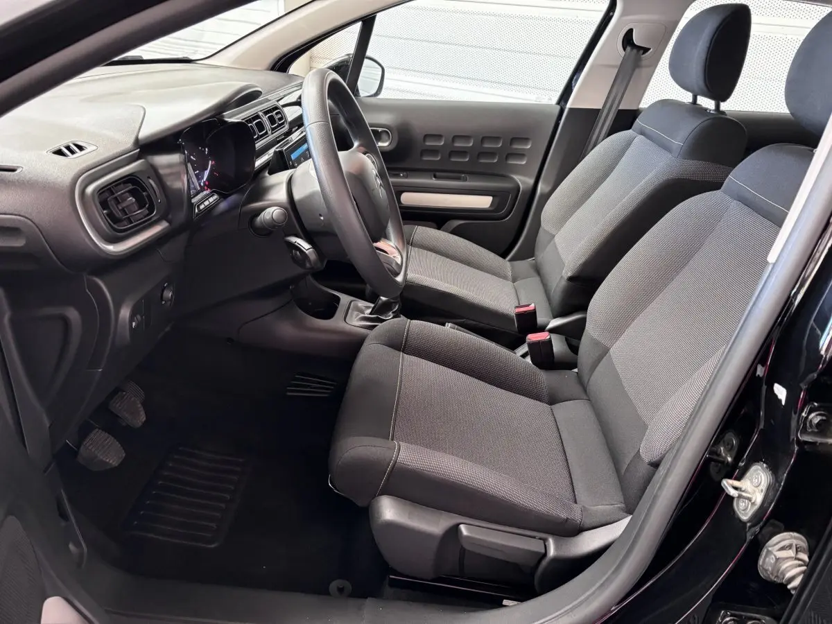 Vue intérieure côté conducteur de la Citroën C3 PureTech 110 noire, montrant sièges tissu et tableau de bord moderne.