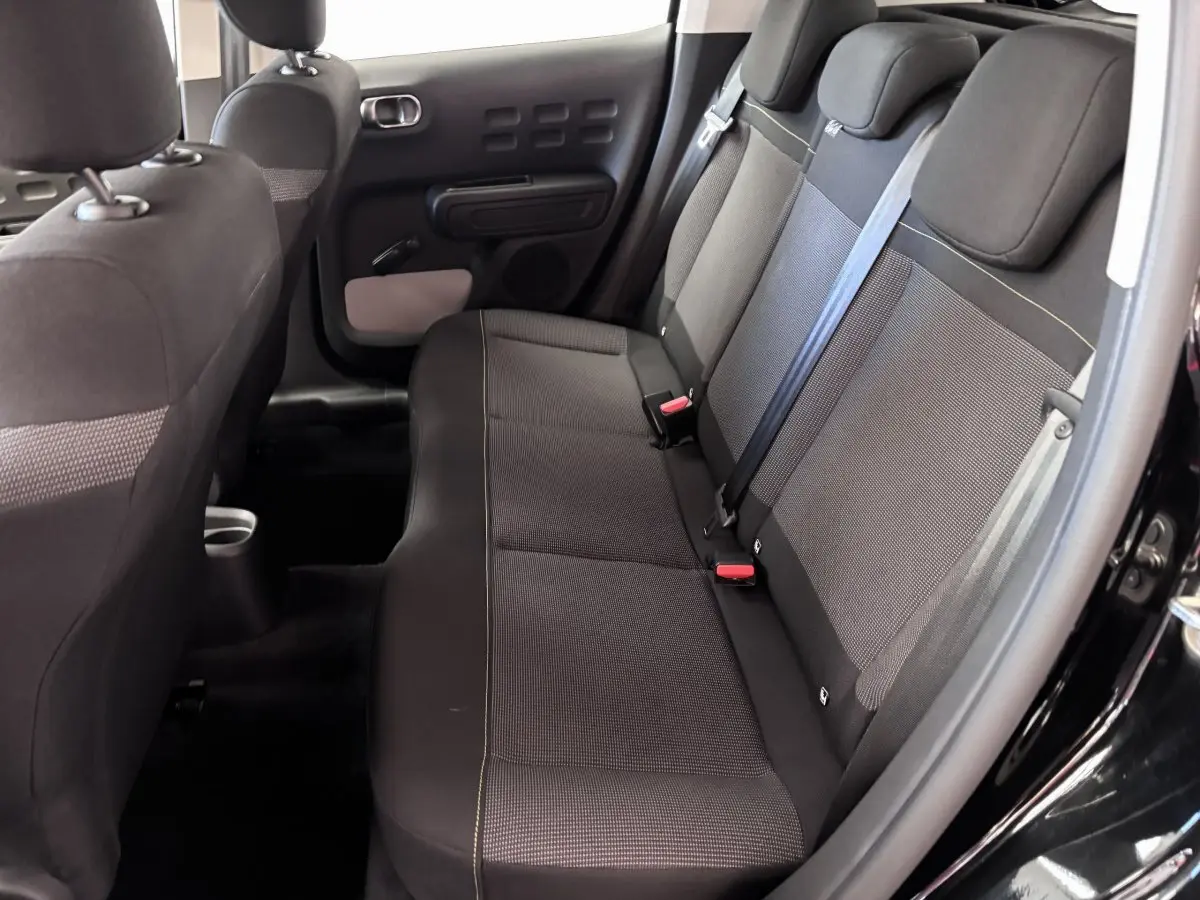 Vue intérieure côté droit des sièges arrière noirs de la Citroën C3 PureTech 110 BVM6 PLUS 2024 avec ceintures et appuie-têtes.