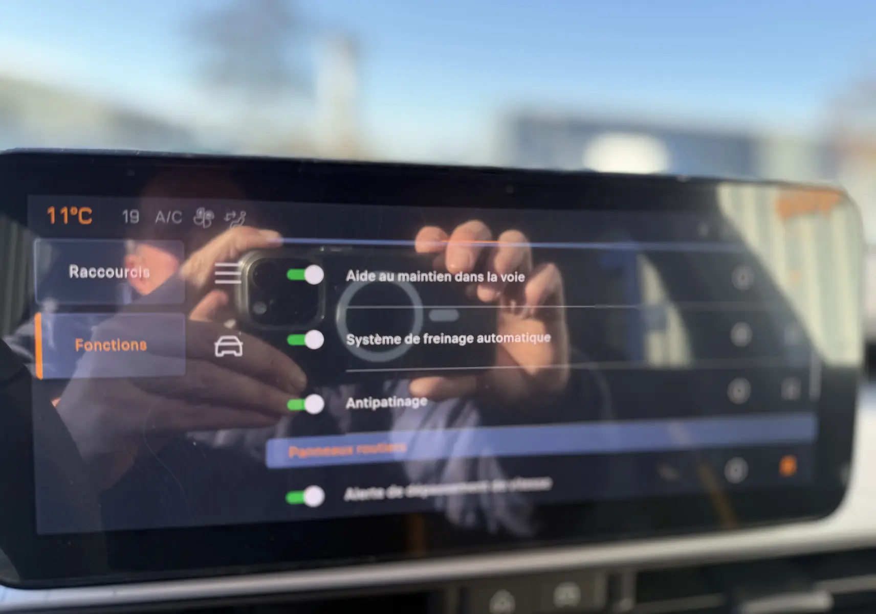 Écran tactile intérieur du Jeep Avenger 2025 affichant les options d’aide à la conduite avec reflet de mains.