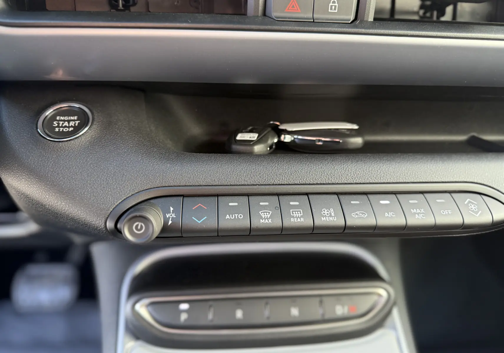 Vue rapprochée de la console centrale gris Storm Grey du Jeep Avenger 2025, avec boutons de climatisation et bouton start/stop.