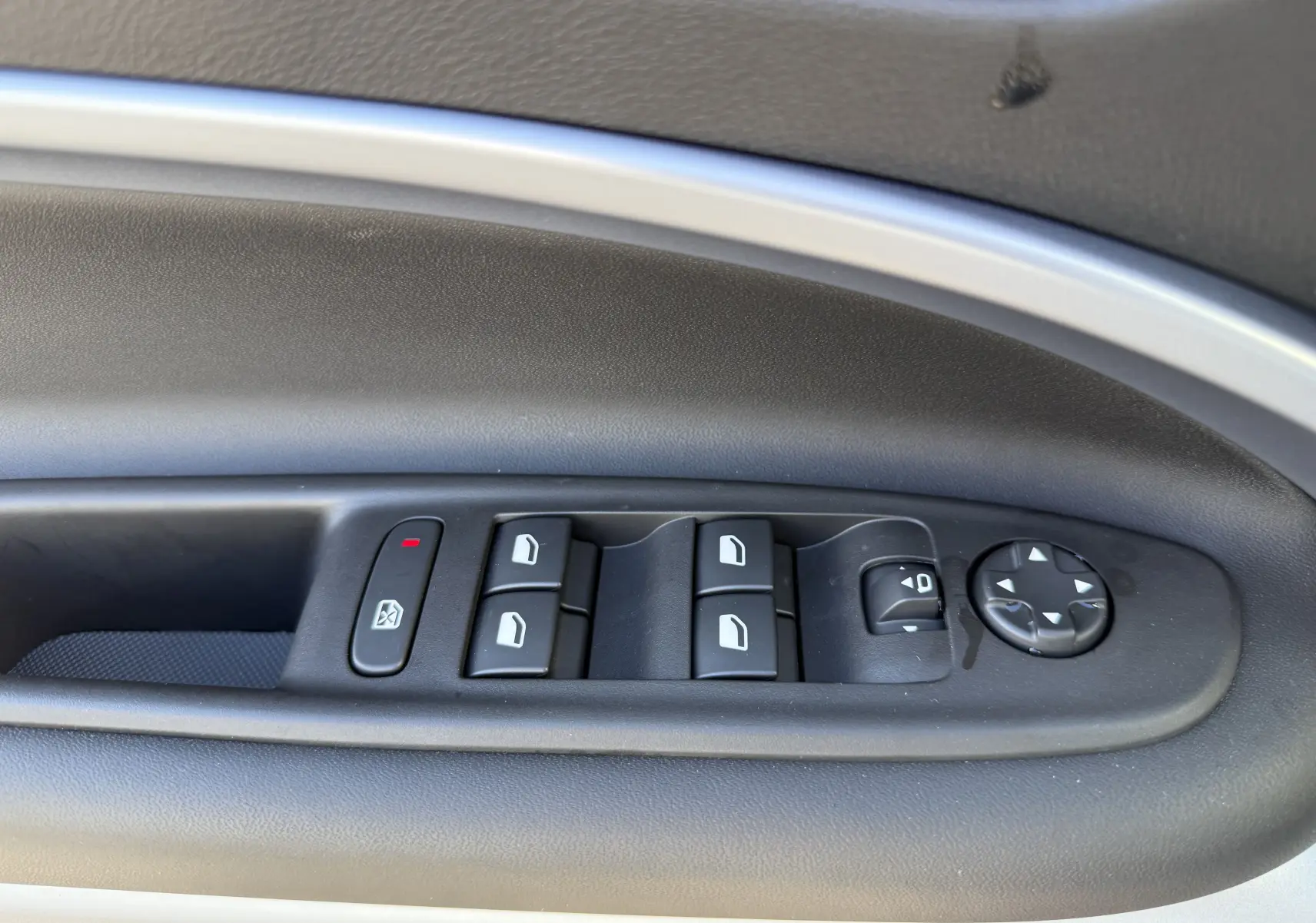 Gros plan sur les commandes de lève-vitres et réglage des rétroviseurs côté gauche intérieur du Jeep Avenger Storm Grey.