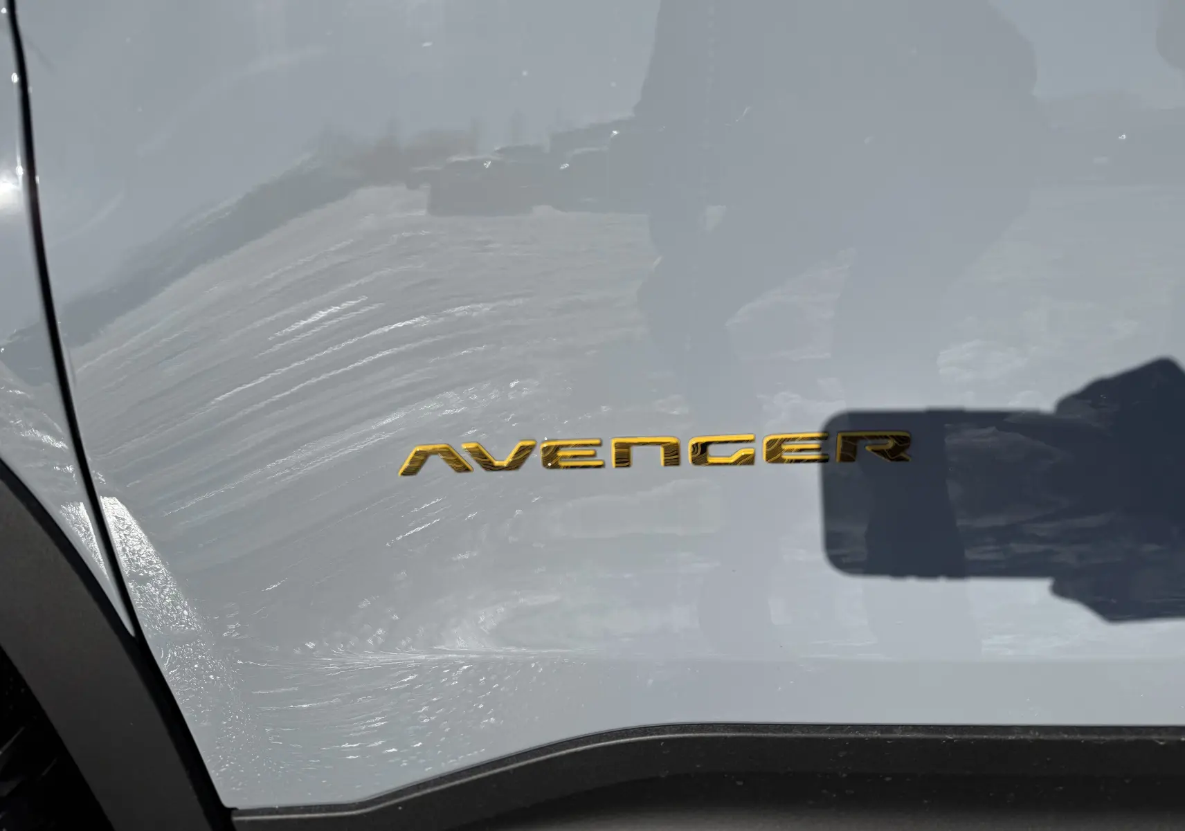 Gros plan sur l’inscription dorée Avenger sur la portière côté gauche d’un Jeep Avenger Storm Grey.