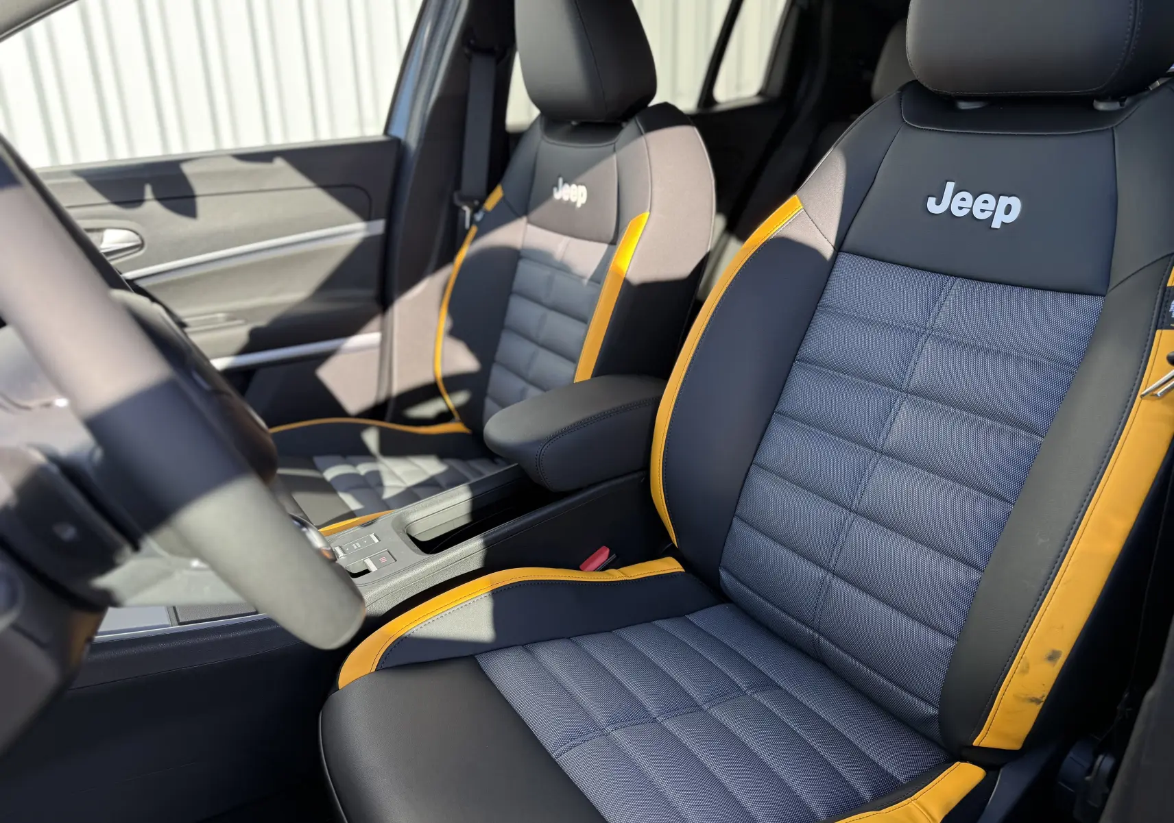 Vue intérieure en gros plan des sièges avant du Jeep Avenger 2025, avec sellerie noire et grise soulignée de bandes jaunes.