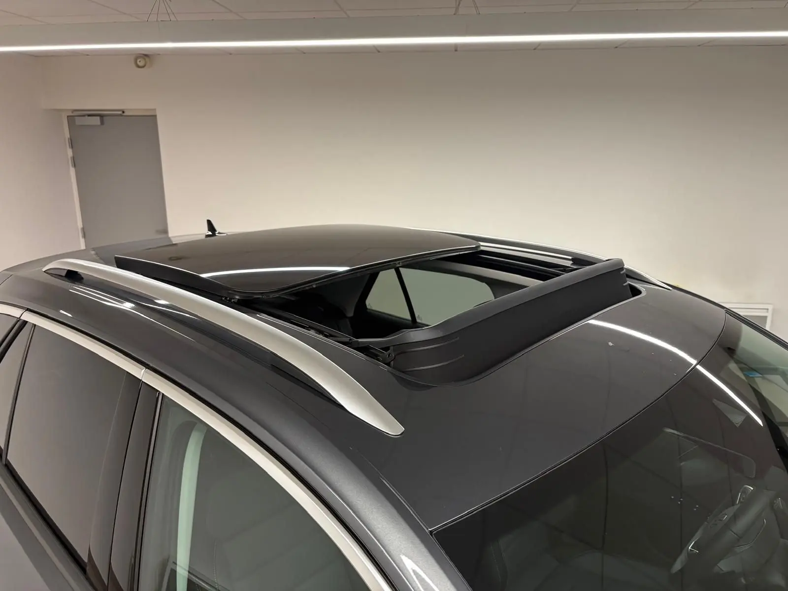Toit ouvrant panoramique ouvert sur le dessus d’un Volkswagen T-Roc gris Indium vu en léger plongé intérieur.