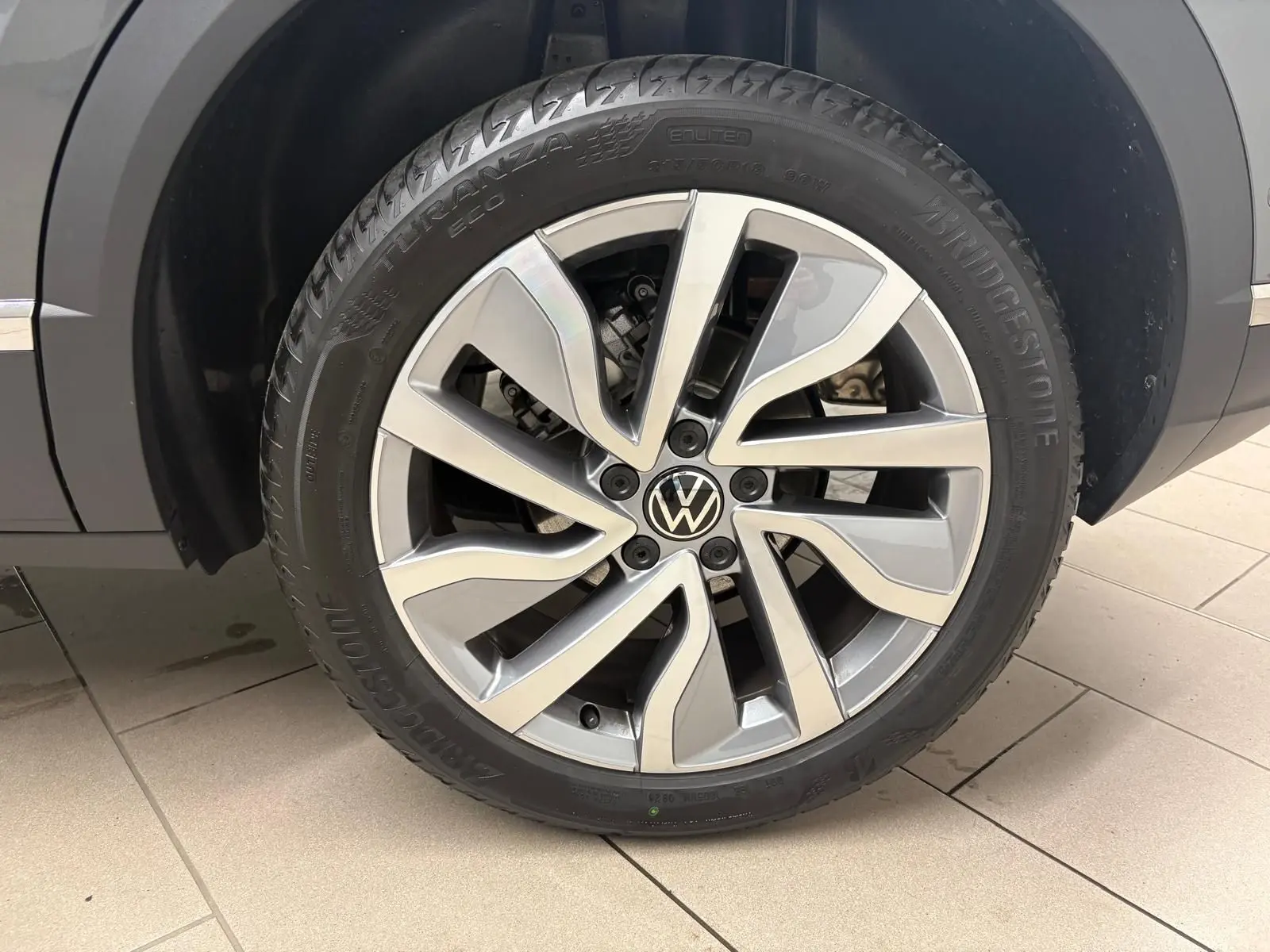 Gros plan sur la roue avant droite du Volkswagen T-Roc 2025 gris Indium avec jante alliage et pneu Bridgestone.