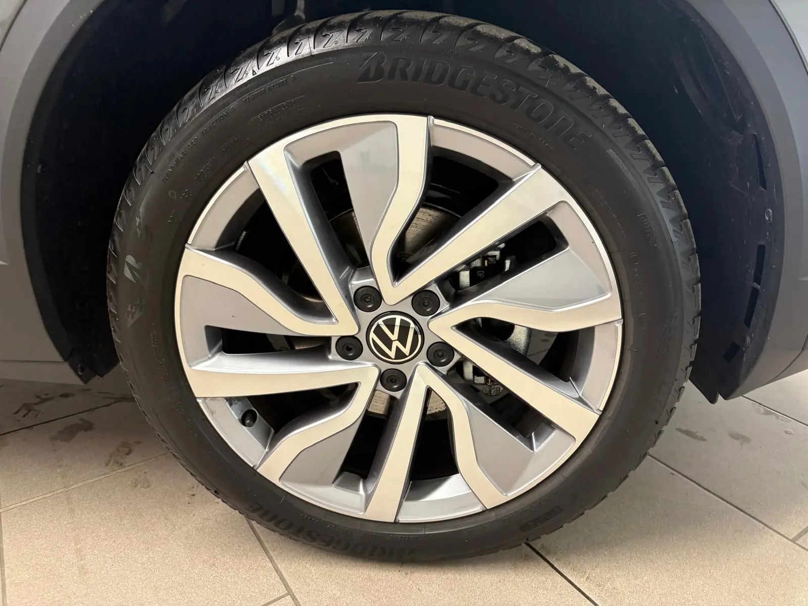 Gros plan sur la roue avant droite du Volkswagen T-Roc 2025 gris Indium avec jante alliage et pneu Bridgestone.