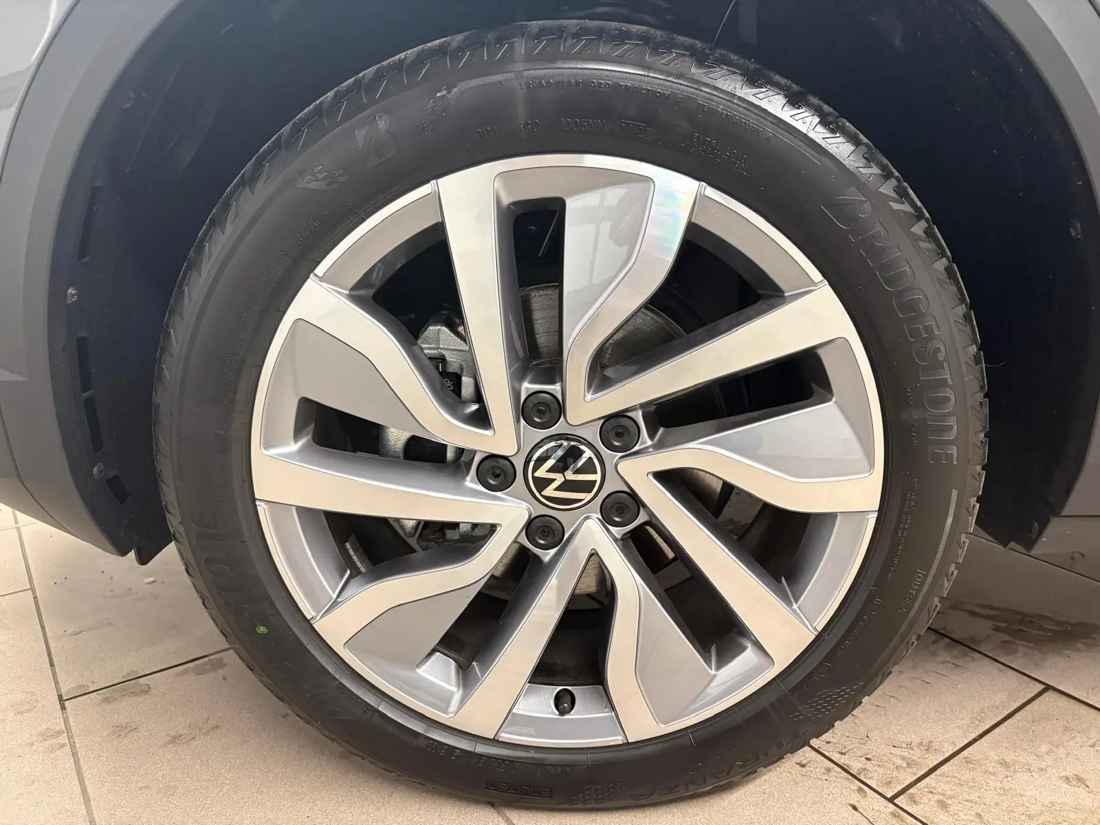 Gros plan sur la jante alliage du Volkswagen T-Roc 2025 en Gris Indium, avec pneu Bridgestone visible.