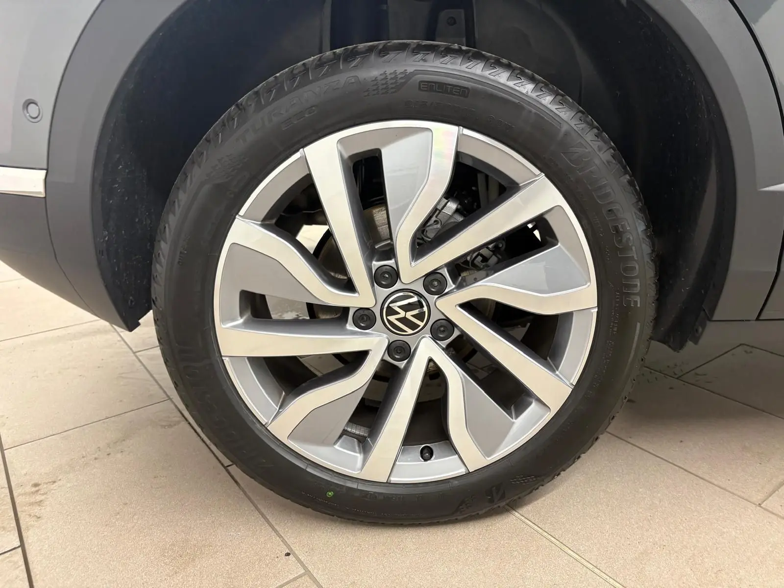 Gros plan sur la roue avant droite du Volkswagen T-Roc 2025 gris Indium avec jante alliage distinctive.