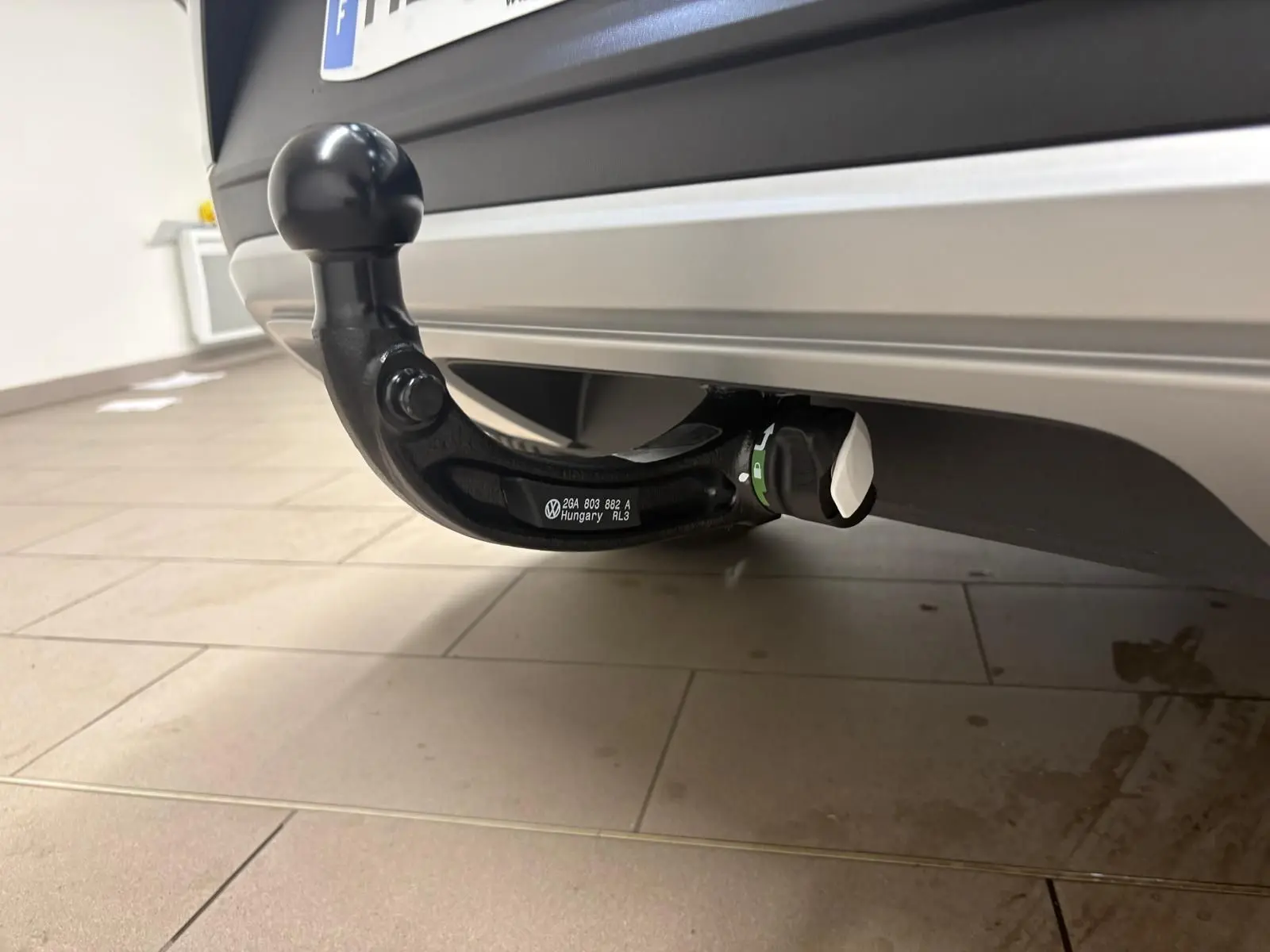 Gros plan sur l'attelage amovible noir sous le pare-chocs arrière d'un Volkswagen T-Roc gris Indium.