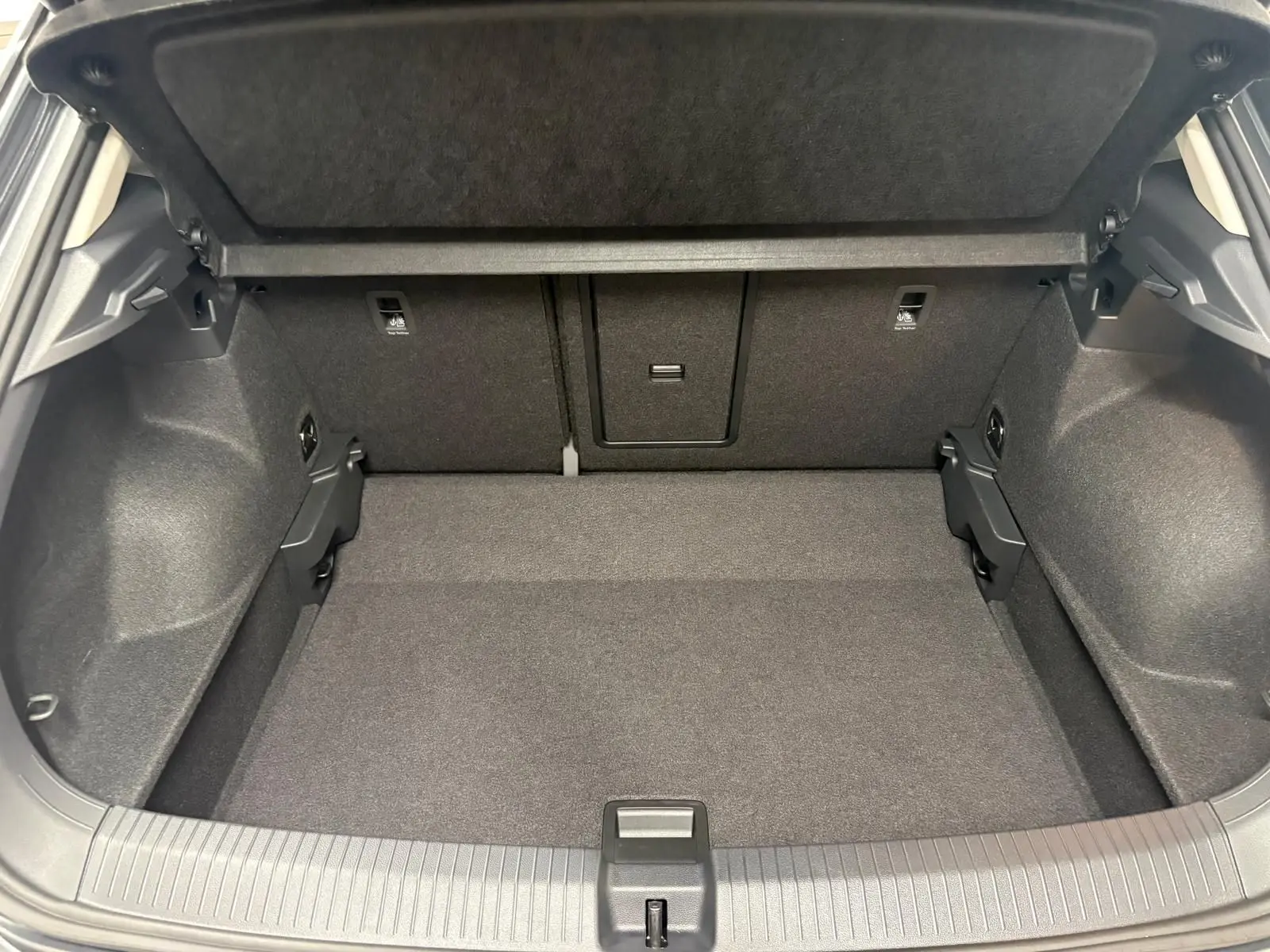 Vue intérieure du coffre spacieux et propre du Volkswagen T-Roc 2025, avec habillage noir uniforme et banquette arrière rabattable.