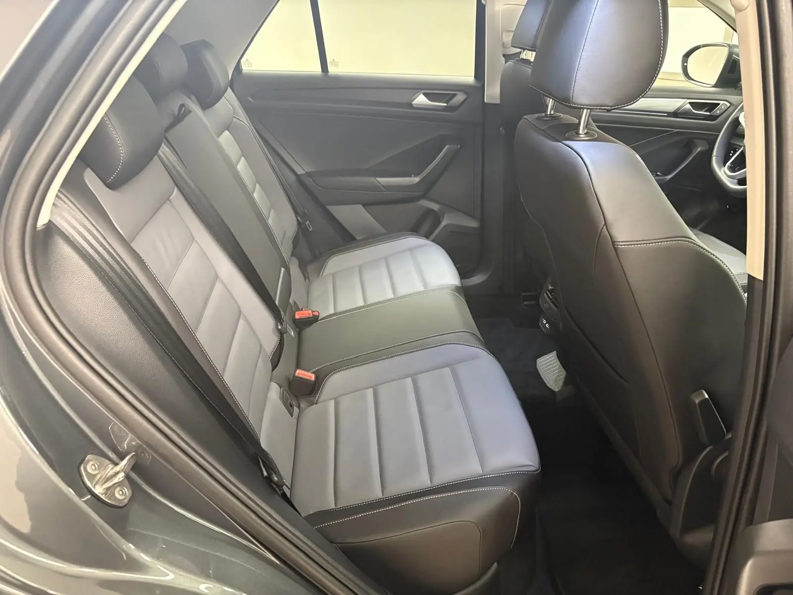 Vue intérieure côté gauche montrant la banquette arrière en cuir gris et noir du Volkswagen T-Roc 2025.