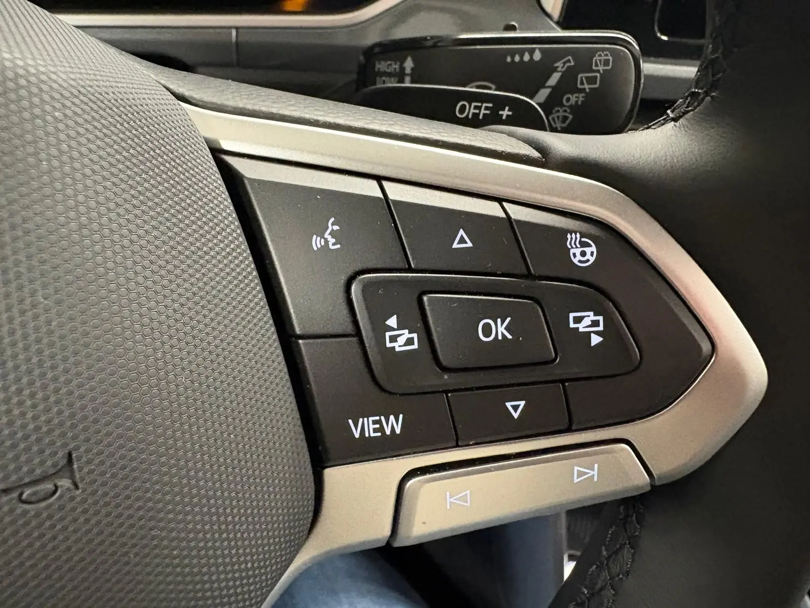 Gros plan sur les commandes au volant du Volkswagen T-Roc 2025, avec finition gris Indium et boutons multifonctions visibles.