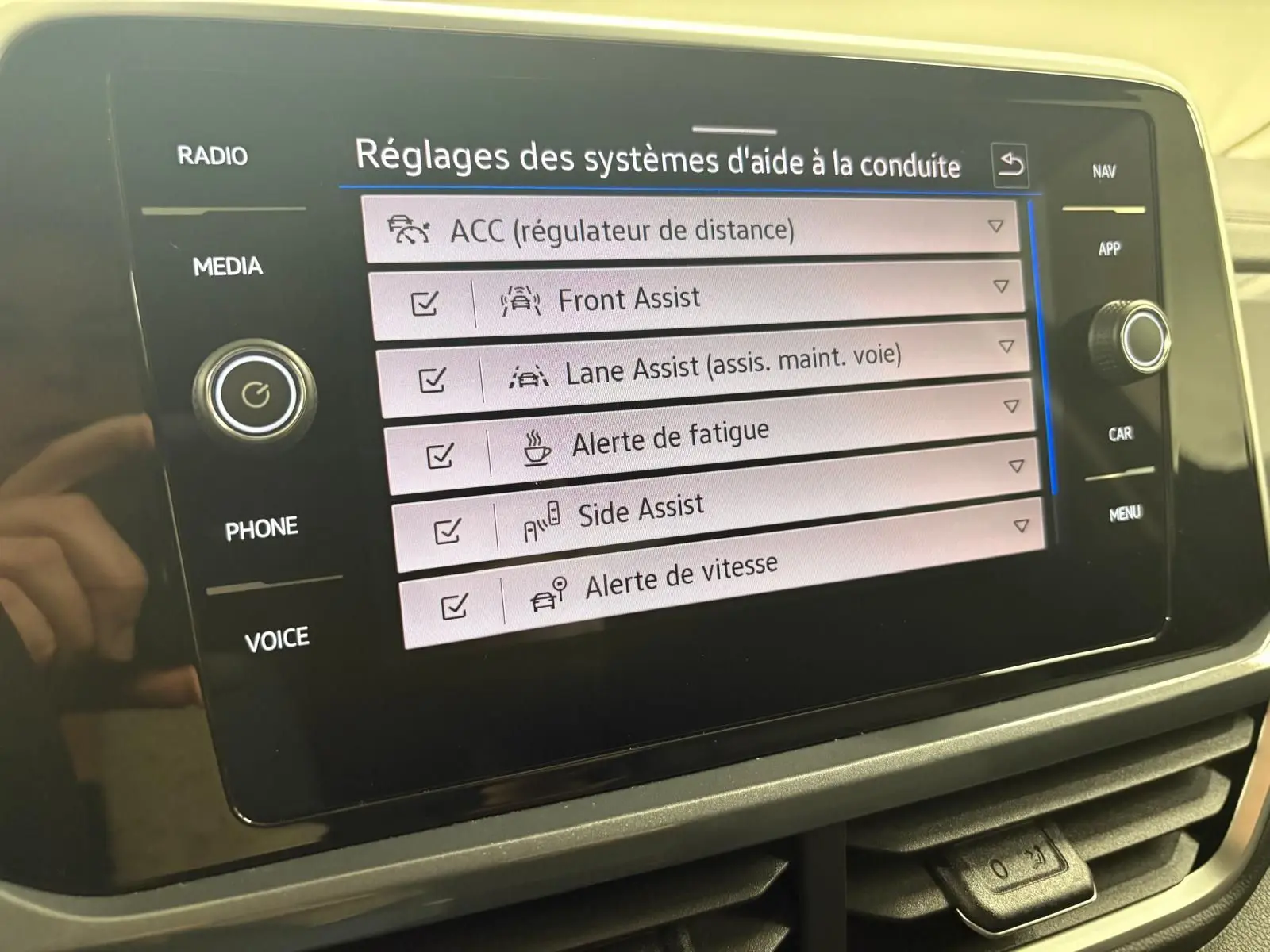 Écran tactile du tableau de bord du Volkswagen T-Roc 2025 affichant les réglages des aides à la conduite.