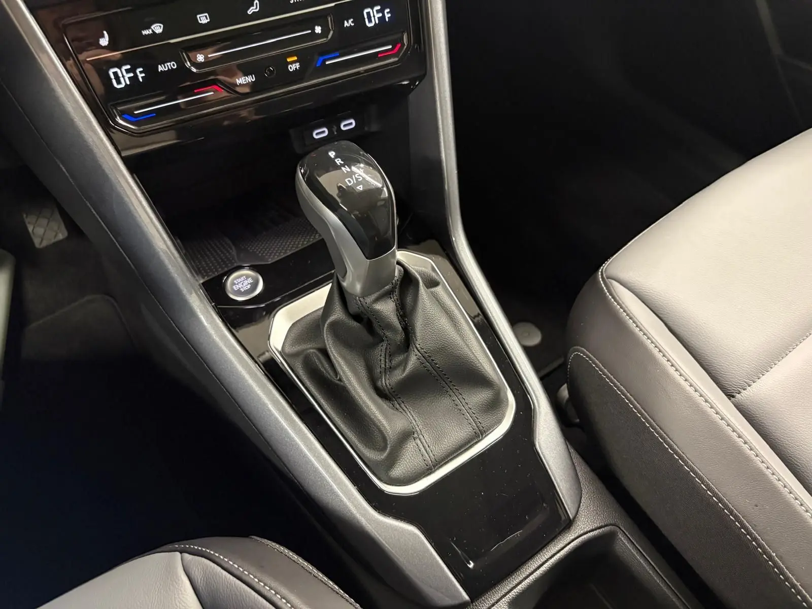 Gros plan sur la console centrale du Volkswagen T-Roc 2025 avec levier de boîte auto et sièges cuir gris.