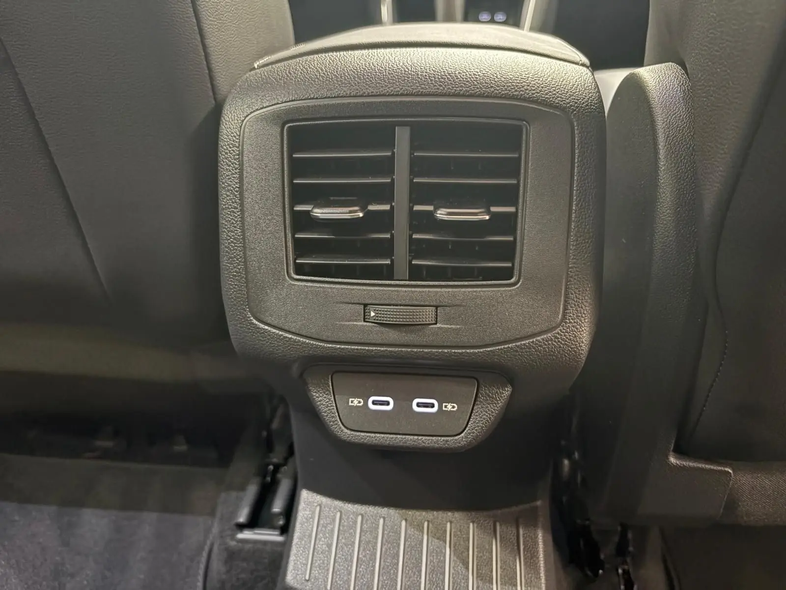 Vue rapprochée de la console arrière du Volkswagen T-Roc gris Indium, avec bouches d’aération et ports USB visibles.